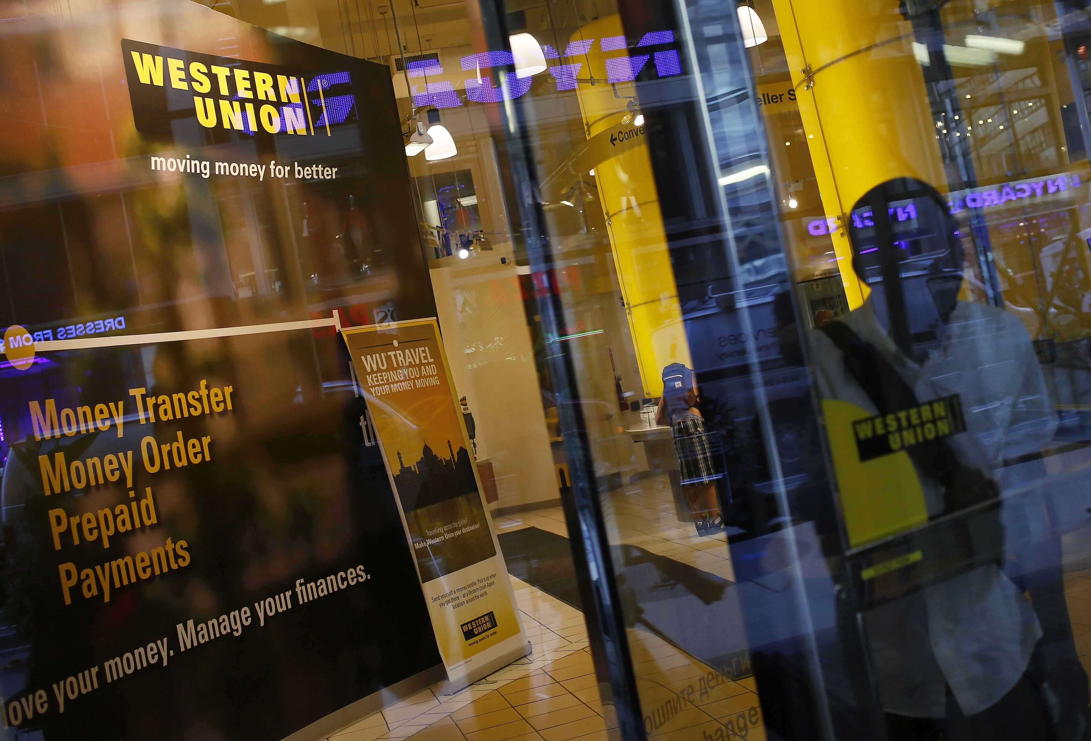 A person walks out of a Western Union branch in New York July 30, 2013. Western Union Co, the world's largest money-transfer company, reported a 27 percent decline in quarterly profit July 30, 2013 after cutting prices and spending more on its online business to compete with more nimble rivals. REUTERS/Shannon Stapleton (UNITED STATES - Tags: BUSINESS)