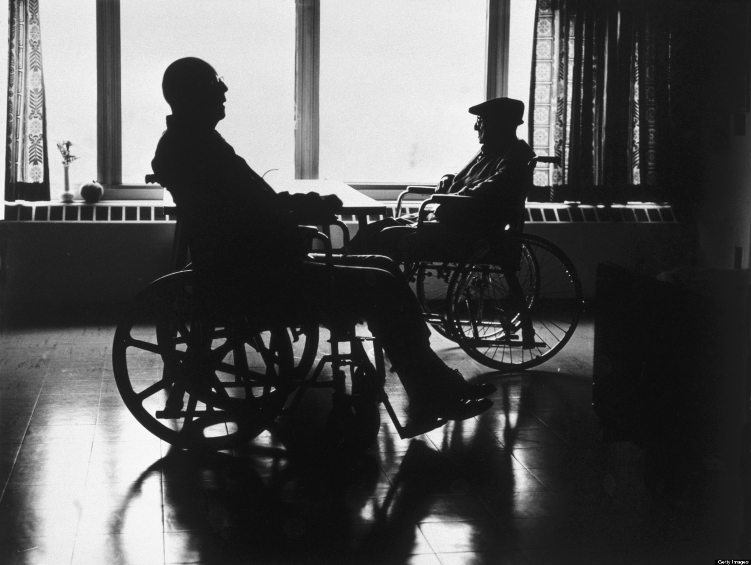 Silhouette of two men in wheelchairs