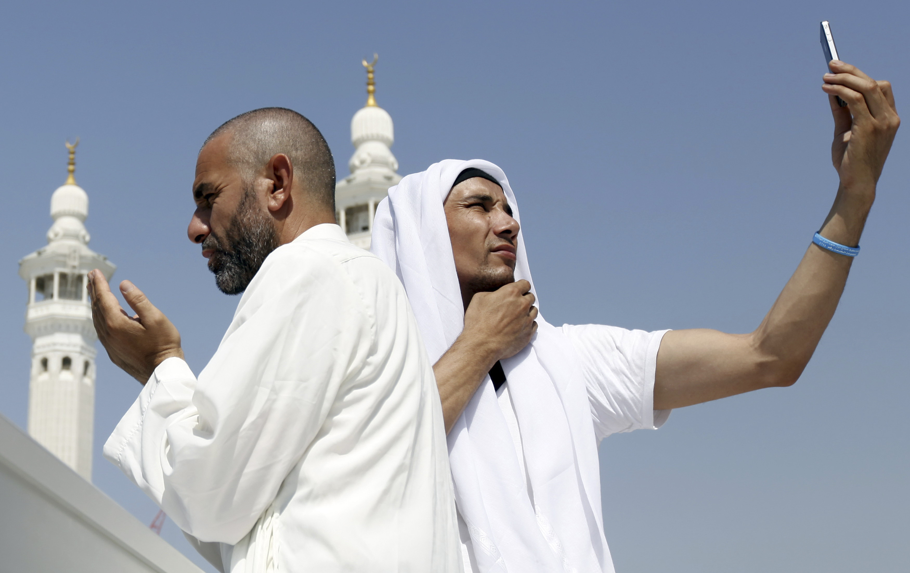 A Muslim pilgrim prays as another takes a photo with his mobile phone at the Grand Mosque during Tawaf al-Wadaa (Farewell Tawaf) on the last day of the annual haj pilgrimage in the holy city of Mecca October 29, 2012. REUTERS/Amr Abdallah Dalsh (SAUDI ARABIA - Tags: RELIGION TPX IMAGES OF THE DAY) - RTR39QGZ